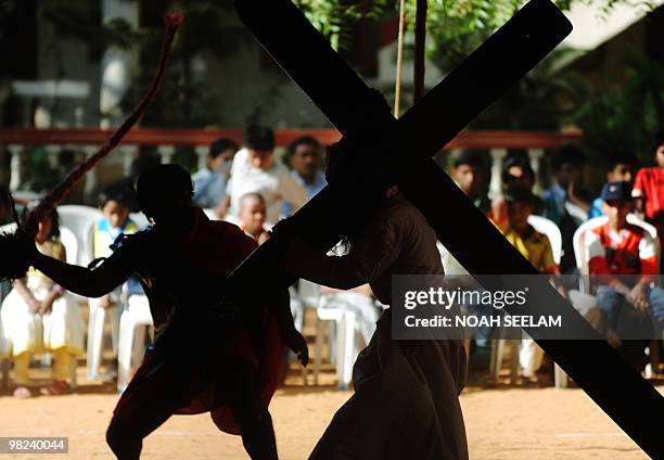 Indian children watch as a man dressed as a Roman soldier whips a man dressed as Jesus Christ and carrying a cross as Catholics re-enact the...