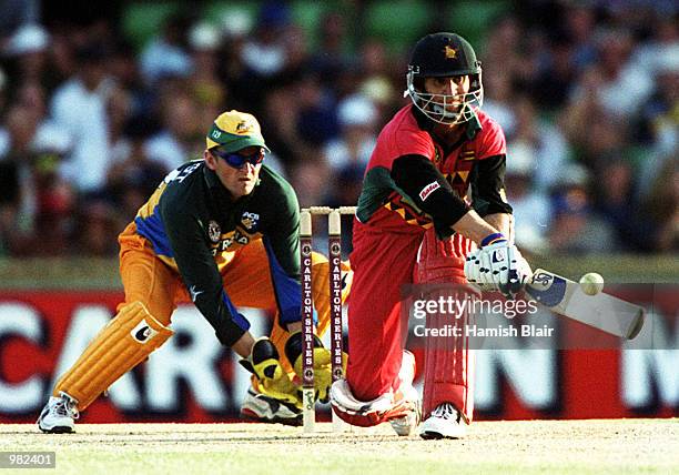 Stuart Carlisle of Zimbabwe plays a reverse sweep during his innings of 119 as wicketkeeper Adam Gilchrist looks on during the Carlton Series One Day...