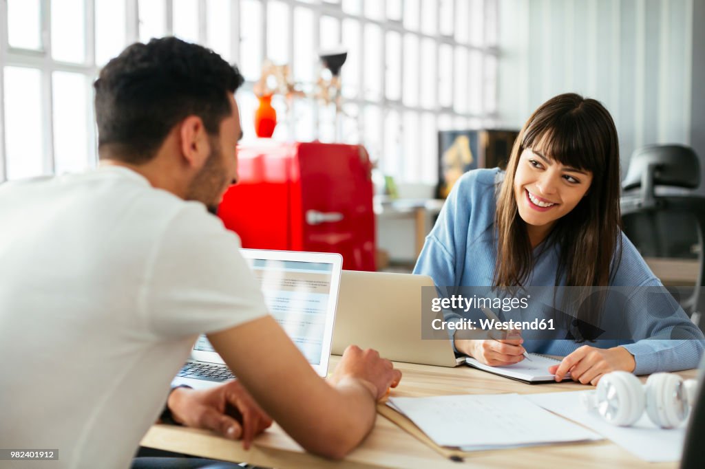 Smiling colleagues working at desk in office