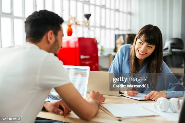 smiling colleagues working at desk in office - conquista fotografías e imágenes de stock