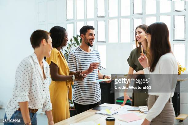smiling colleagues working together at desk in office discussing papers - casual clothing stock pictures, royalty-free photos & images