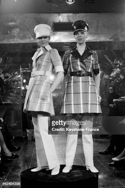 Mannequins présentant deux modèle Ted Lapidus : des ensembles avec vestes à carreaux ceinturées et pantalons assortis et casquettes en cuir, en...