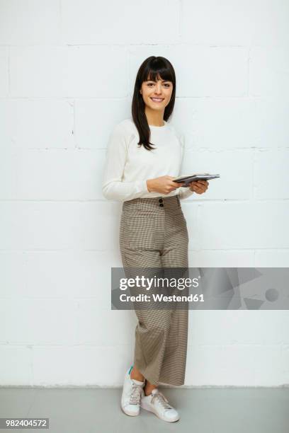 portrait of smiling young woman with notebook standing at brick wall - estar de pie fotografías e imágenes de stock