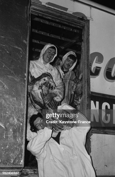 Bouchers déchargeant un quartier de viande d'un camion frigorifique avant le déménagement pour Rungis à Paris en France, le 28 février 1969.