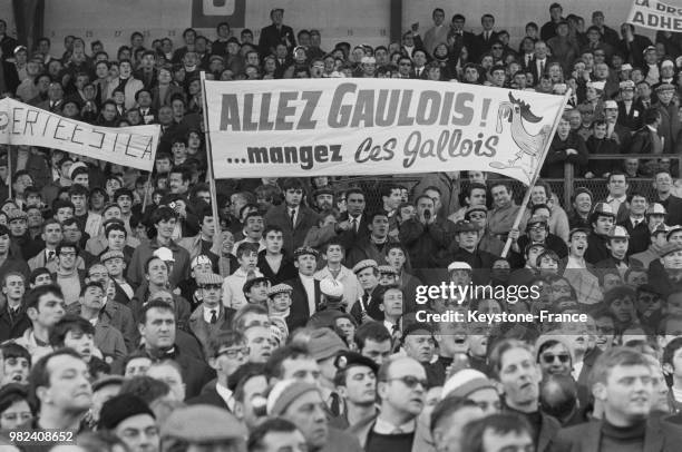 Les spectateurs tenant une banderole sur laquelle est inscrit 'Allez Gaulois ! ... Mangez ces Gallois' lors du match de rugby France - Pays de Galles...