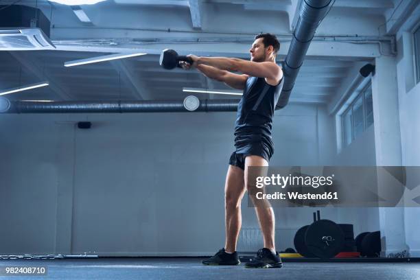 athletic man doing kettlebell swing exercise at gym - kugelhantel stock-fotos und bilder