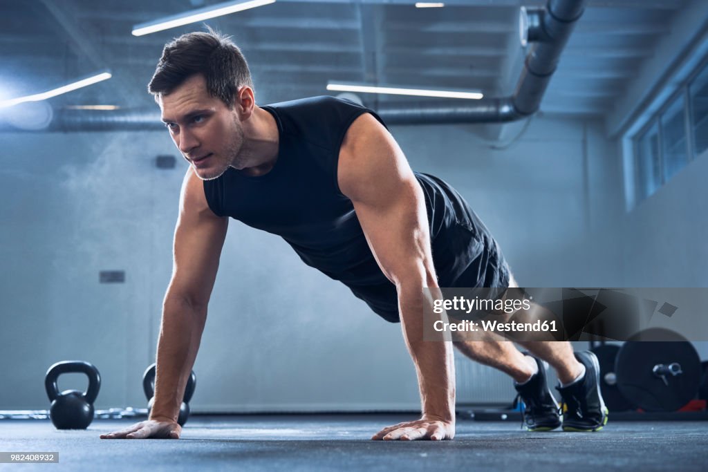 Athletic man doing pushups exercise at gym
