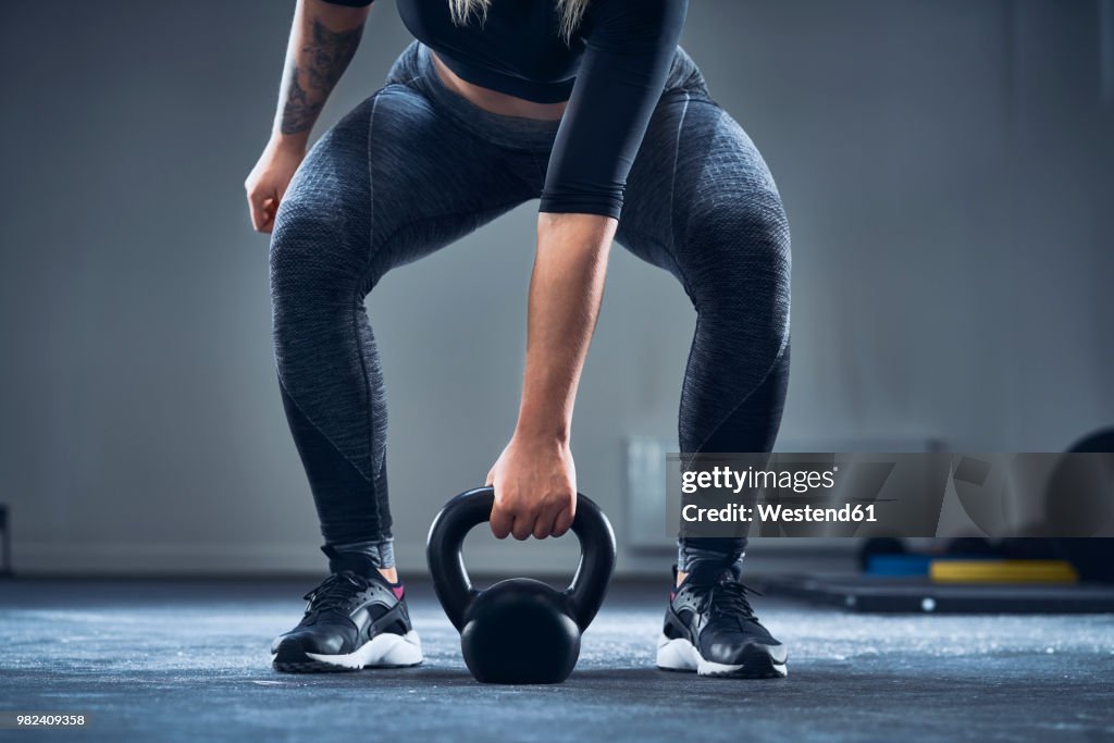 Close-up of athletic woman exercising with kettlebell at gym