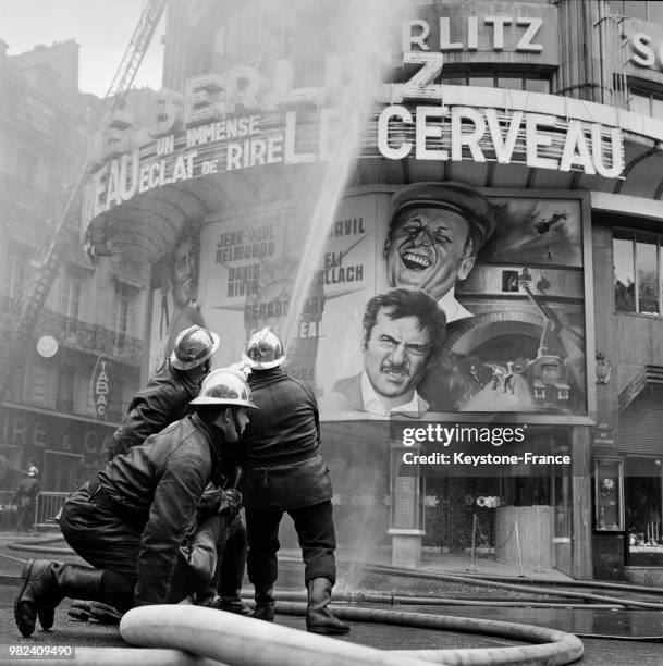 Les pompiers dirigent une des lances vers les étages lors de l'incendie à l'école Berlitz à Paris en France, le 11 avril 1969 - En arrière-plan,...