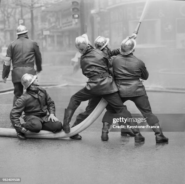 Les pompiers dirigent une des lances vers les étages lors de l'incendie à l'école Berlitz à Paris en France, le 11 avril 1969.