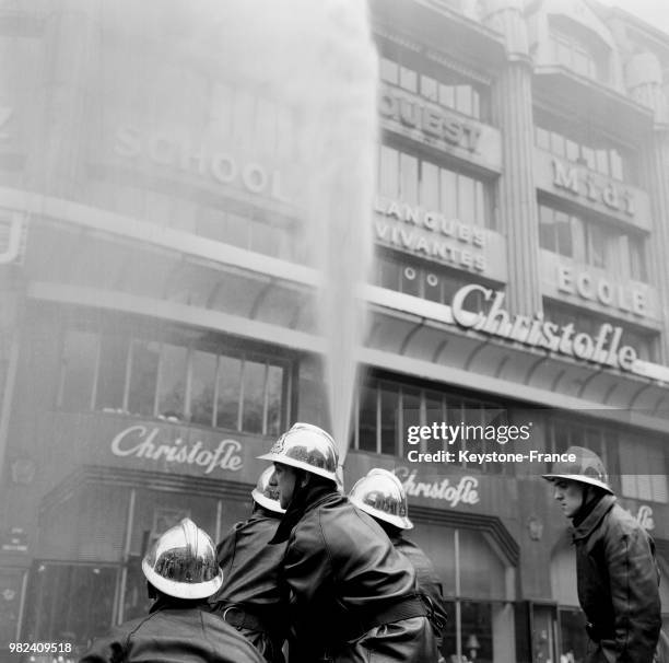 Les pompiers dirigent une des lances vers les étages lors de l'incendie à l'école Berlitz à Paris en France, le 11 avril 1969.