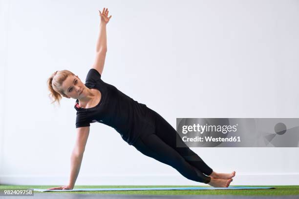 woman doing side plank yoga exercise in studio - side plank pose stock pictures, royalty-free photos & images