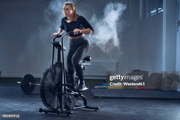 athletic woman doing air bike workout at gym - cycling gym stock pictures, royalty-free photos & images