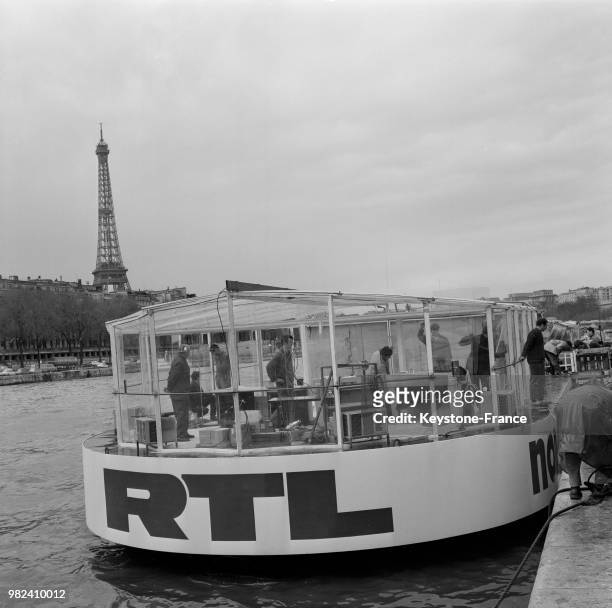 Le nouveau studio flottant de RTL arrimé à un bateau-mouche à Paris en France, le 12 avril 1969, avec la Tour Eiffel en arrière-plan.