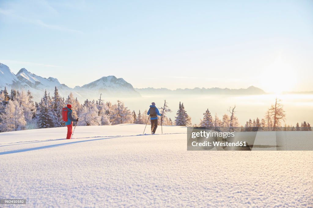 Austria, Tyrol, snowshoe hikers at sunrise