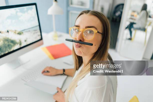 portrait of funny young woman at desk pouting mouth - konzepte und themen stock-fotos und bilder