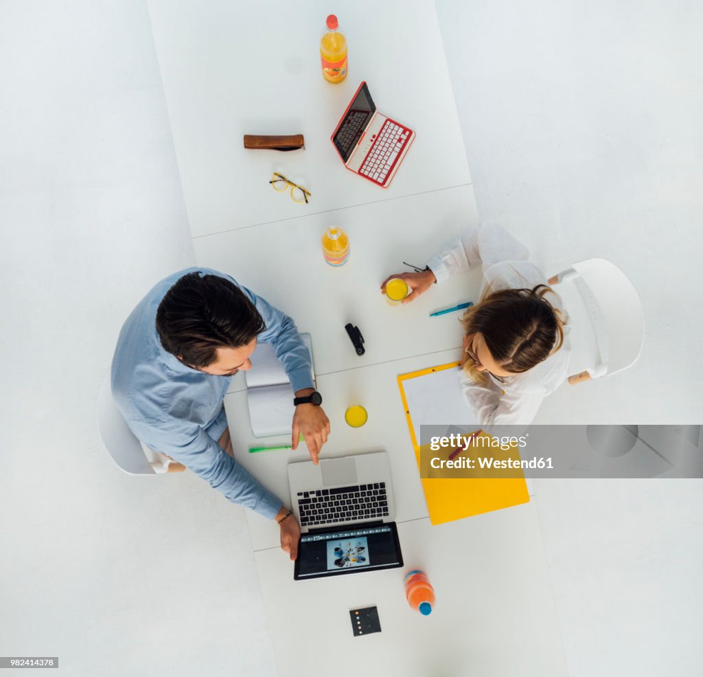Two business people at meeting table in office, top view