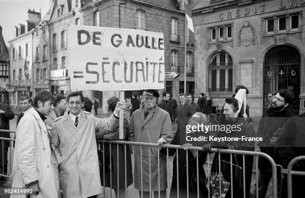 Scène de rue avec un homme tenant un panneau portant l'inscription 'De Gaulle = sécurité', lors du discours du général Charles de Gaulle en visite en...
