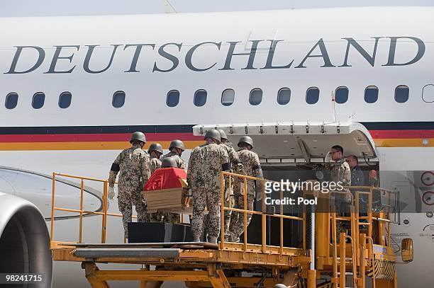 The coffin of a killed Bundeswehr soldier is loaded by German soldiers in the presence of German development minister Dirk Niebel at the airport of...