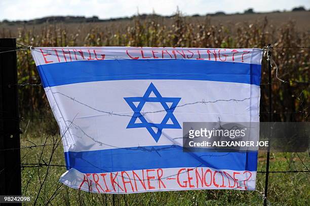 An Israeli flag inscribed with the words "Ethnic Cleansing" and "Afrikaner-Genocide?" is pictured hung on the fence of farmer and far right-wing...