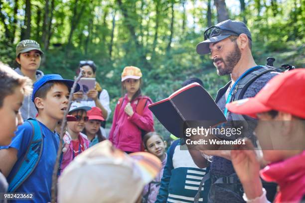 man reading to kids on a field trip in forest - field trip stock pictures, royalty-free photos & images