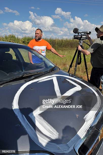 South African sporting a t-shirt with a former apartied flag walks past a camera near his car incribed with the logo of the Afrikaner...