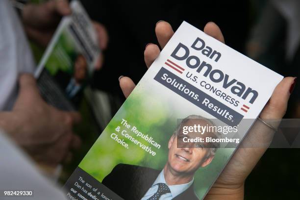 Volunteer holds a pamphlet for Representative Dan Donovan, a Republican from New York, during a campaign stop at the Mount Loretto Food Truck...