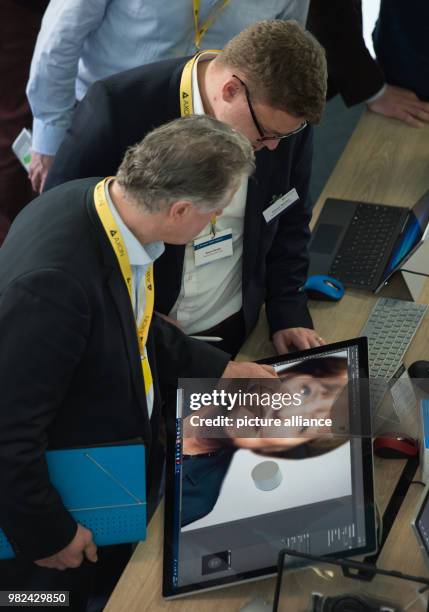 Visitors have a look at the Computer Surface Studio, which shows an image of German Chancellor Merkel at the stand of software producer Microsoft...