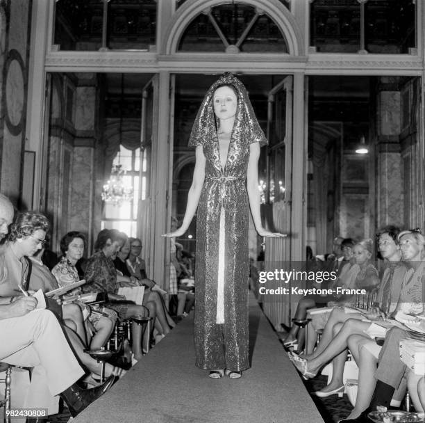 Modèle portant une robe du soir et un pantalon en lame lors du défilé de Jacques Esterel à l'hôtel de Crillon, à Paris, en 1969, France.