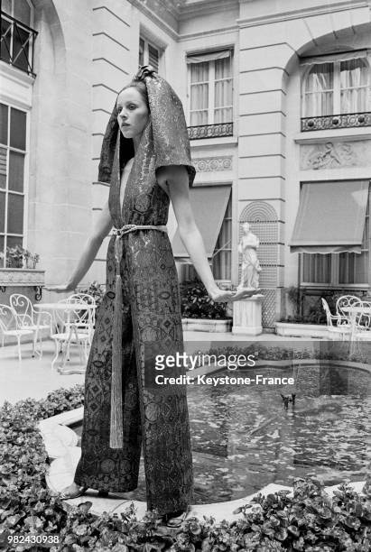 Modèle portant une robe du soir et un pantalon en lame lors du défilé de Jacques Esterel à l'hôtel de Crillon, à Paris, en 1969, France.
