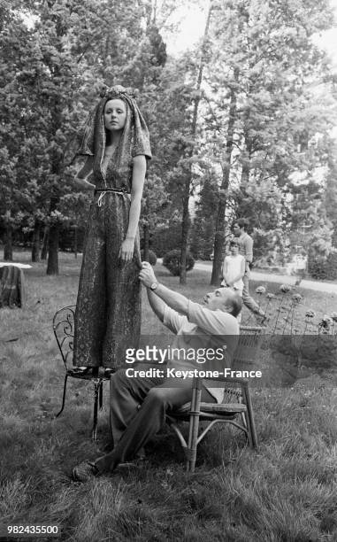 Jacques Esterel faisant des essayages avec une robe du soir et un pantalon à lames, en 1969, France.