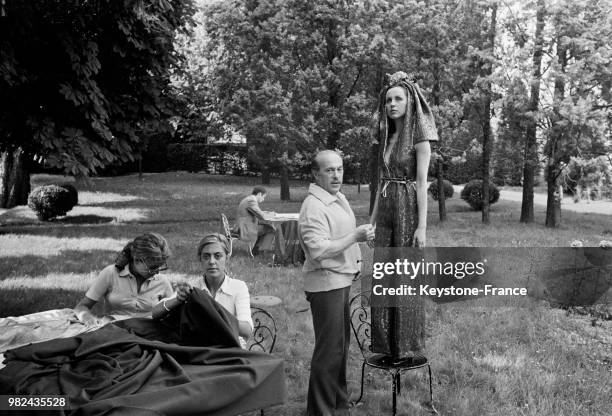 Jacques Esterel faisant des essayages avec une robe du soir et un pantalon à lames, en 1969, France.