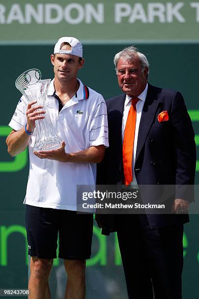 Andy Roddick of the United States holds his trophy as he stands next to Butch Buchholz after the men's final of the 2010 Sony Ericsson Open at...