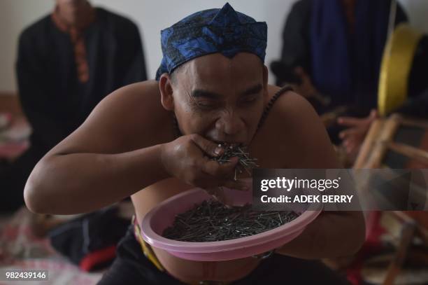 This picture taken on February 4, 2018 shows Indonesian debus fighter Mulyadi eating nails during a skills demonstration in Bandung. - Many outside...