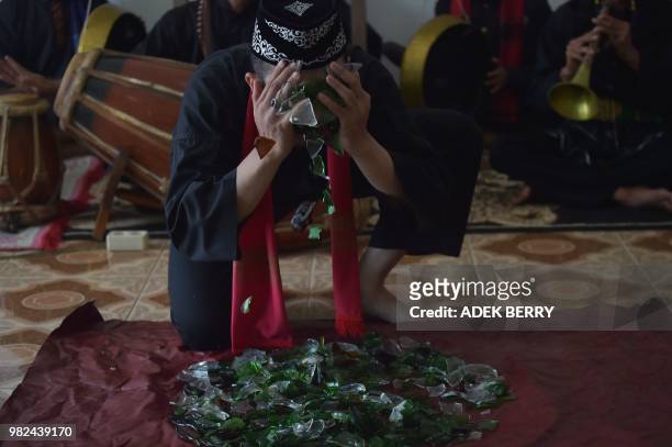 This picture taken on February 4, 2018 shows Indonesian debus master Aris Afandi putting broken glass on his face during a skills demonstration in...