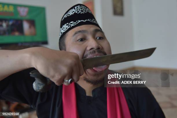 This picture taken on February 4, 2018 shows Indonesian debus master Aris Afandi showing his skill "unhurt" while cutting his tongue with a blade...