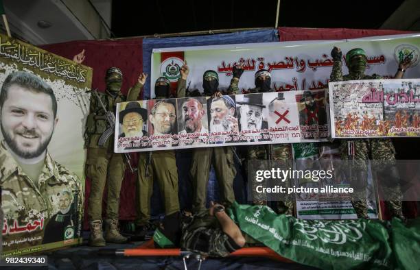 Armed members of Izz ad-Din al-Qassam Brigades, the military wing of the Hamas Palestinian Islamist movement, stand next to a poster of 26-year-old...