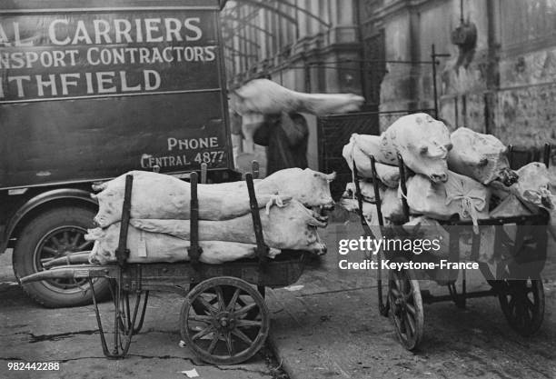 Marché de la viande dans le quartier de Smithfield carcasses de porcs empilées sur des charettes à Londres en Angleterre au Royaume-Uni, en 1936.