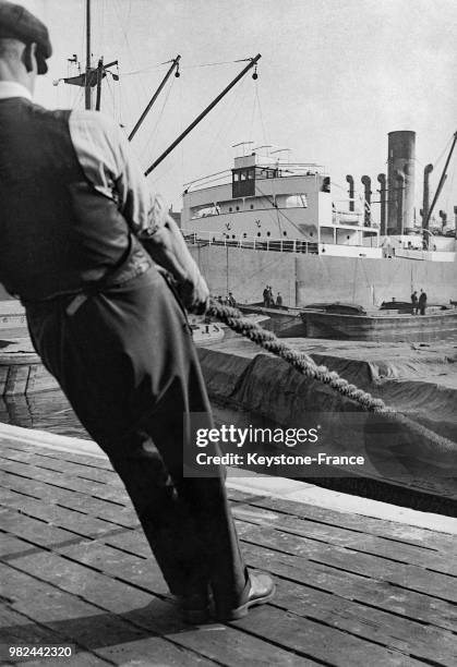 Homme tirant une amarre sur les docks à Londres en Angleterre au Royaume-Uni, en 1936.