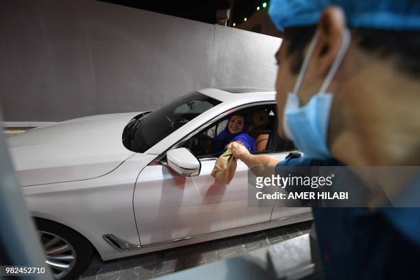 Saudi Samira Al-Ghamdi is seen in her car receiving her food order from a fast food in the coastal city of Jeddah for the first time. Little after...