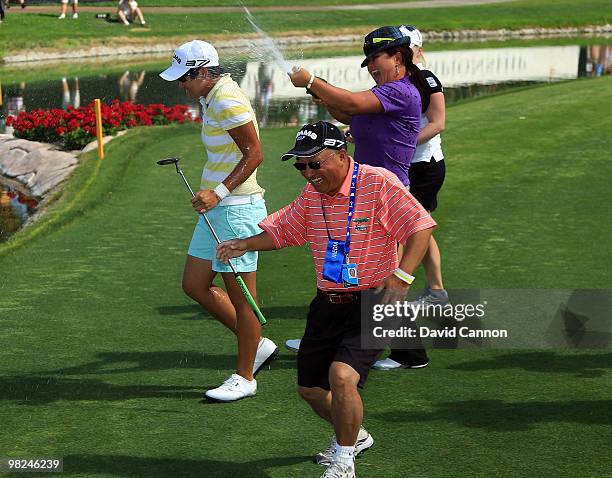 Yani Tseng of Taiwan is chased by fellow LPGA player Christina Kim after as Yani Tseng's father takes evasive action after Tseng had holed the...