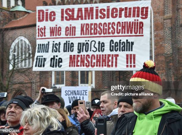 Right-wing group carries a banner reading 'Die Islamisierung ist wie ein Krebsgeschwür und ist die größte Gefahr für die Menschheit' to protest...