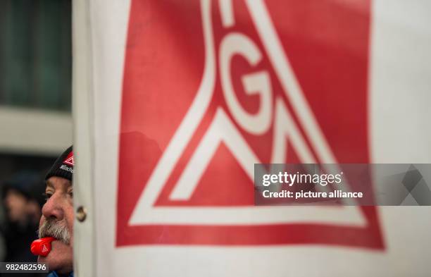 Man blows a whistle next to a flag of the trade union 'IG Metall' in Munich, Germany, 02 February 2018. Unionists from metal, automobile and...