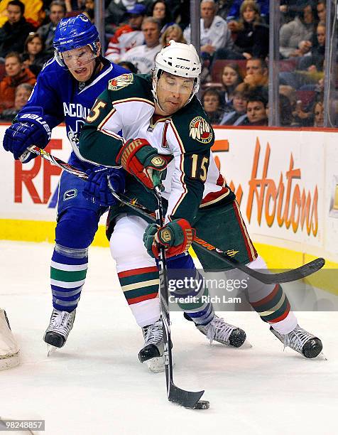 Christian Ehrhoff of the Vancouver Canucks tries to check Andrew Brunette of the Minnesota Wild during the first period of NHL action on April 04,...