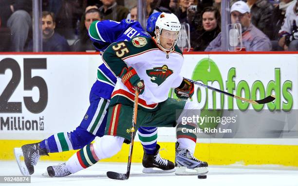 Nick Schultz of the Minnesota Wild tries to fend off Kyle Wellwood of the Vancouver Canucks while trying to get the puck of of his zone during the...