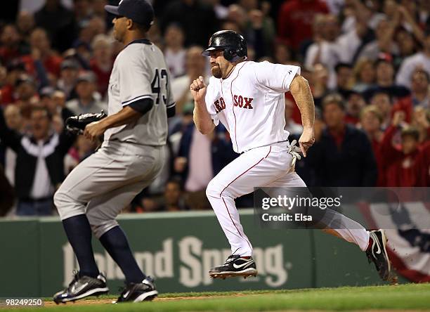 Kevin Youkilis of the Boston Red Sox scores the game winning run as Damaso Marte of the New York Yankees tries to beat him to home plate on April 4,...