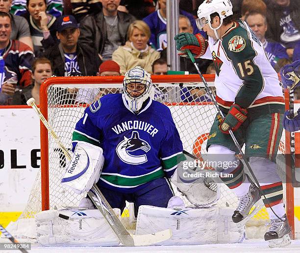 Goalie Roberto Luongo of the Vancouver Canucks gets into position to make a save with Andrew Brunette of the Minnesota Wild in close looking for a...