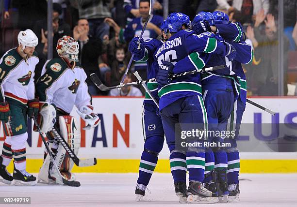 The Vancouver Canucks celebrates while goalie Niklas Backstrom and Kyle Brodziak of the Minnesota Wild skate off the ice after losing in overtime in...