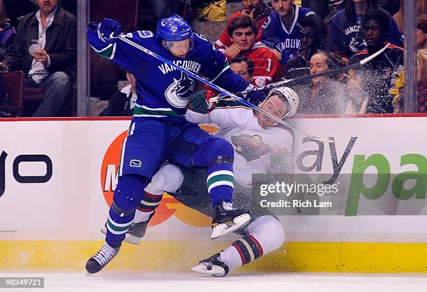 Alexander Edler of the Vancouver Canucks takes down Martin Havlat of the Minnesota Wild along the side boards during the third period of NHL action...