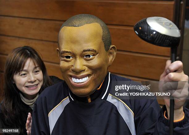 An employee of Japanese toy mask maker Ogawa Rubber wears a rubber mask resembling US top golfer Tiger Woods at the company's factory in Saitama,...